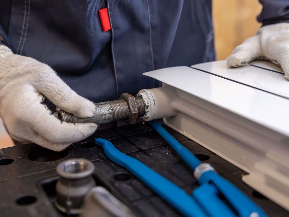 An engineer fitting a radiator pipe during a clean, tidy install